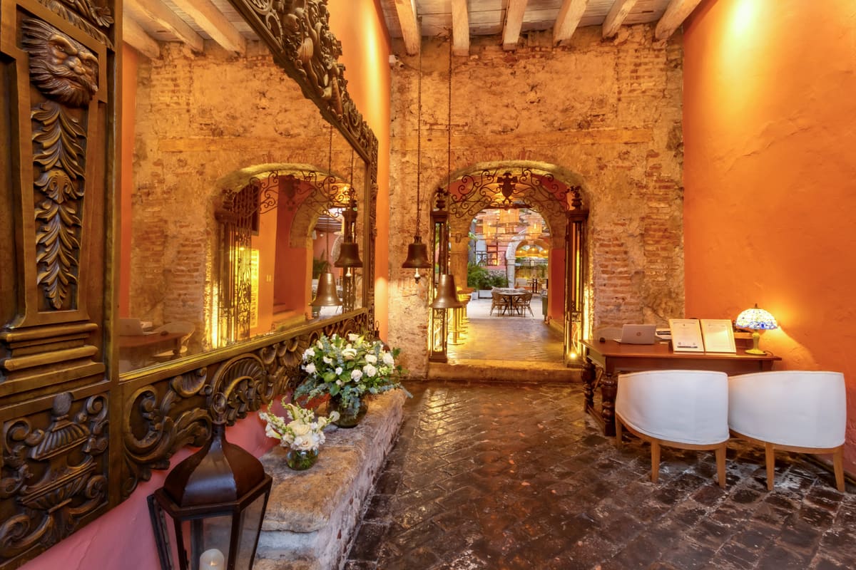 Lobby colonial con marcos dorados y muros de piedra
